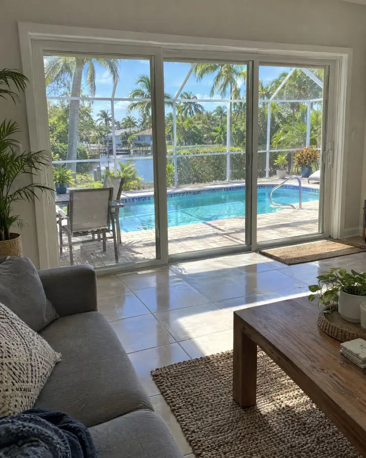 Living room with tall sliding glass doors opening to a pool